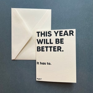 May include: A white card with black text that reads "This year will be better. It has to. Right?"