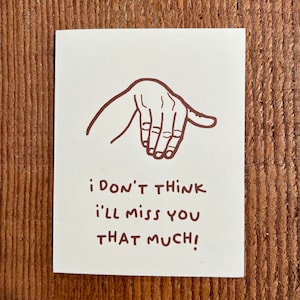 May include: A white card with a brown hand drawn illustration of a hand making a gesture. The text on the card reads "i don't think i'll miss you that much!"