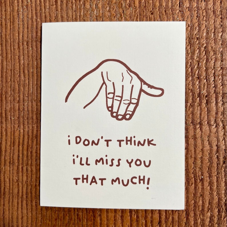 May include: A white card with a brown hand drawn illustration of a hand making a gesture. The text on the card reads "i don't think i'll miss you that much!"
