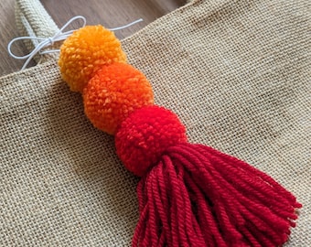 Pom pom tassel bag charm in vibrant red and orange.