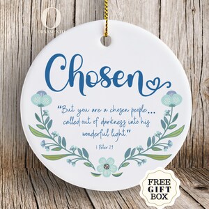 May include: White ceramic ornament with the word "Chosen" in blue script, floral accents, and a Bible verse. The ornament has a gold string for hanging and a "Free Gift Box" sticker.