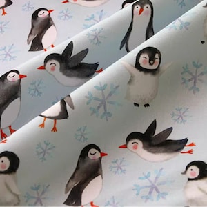 Pode incluir: Um tecido azul claro com um padr&atilde;o repetitivo de pinguins e flocos de neve. Os pinguins est&atilde;o em v&aacute;rias poses, alguns est&atilde;o em p&eacute;, alguns est&atilde;o nadando e alguns est&atilde;o voando. Os flocos de neve s&atilde;o brancos e t&ecirc;m um design delicado.