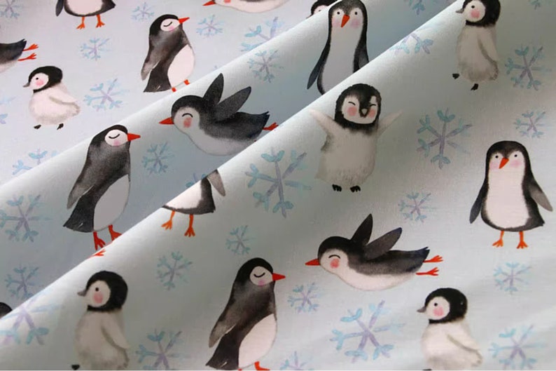 Pode incluir: Um tecido azul claro com um padr&atilde;o repetitivo de pinguins e flocos de neve. Os pinguins est&atilde;o em v&aacute;rias poses, alguns est&atilde;o em p&eacute;, alguns est&atilde;o nadando e alguns est&atilde;o voando. Os flocos de neve s&atilde;o brancos e t&ecirc;m um design delicado.