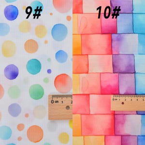 May include: Two fabric swatches with watercolor designs. The left swatch features a white background with colorful polka dots. The right swatch features a rainbow gradient of squares. Both swatches have a ruler for scale.