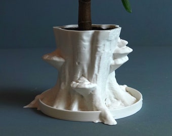 May include: White ceramic planter shaped like a tree stump with a small green plant growing out of the top.