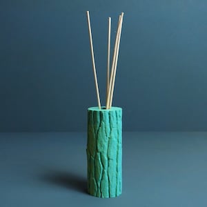 Peut inclure: Un flacon diffuseur vert turquoise avec un motif en bois et cinq bâtonnets en bois qui dépassent du haut.
