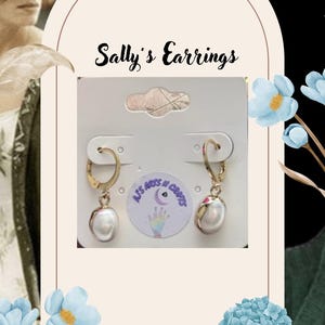 May include: Gold-coloured hoop earrings with a dangling, pear-shaped white pearl. The earrings are displayed on a white card with the text "Sally's Earrings". The background features floral accents and a woman's image.