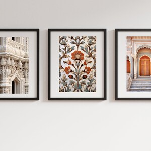 May include: Three framed prints depicting intricate architectural details from India. The left print shows a close-up of a white stone archway with ornate carvings. The centre print features a floral pattern in shades of blue, orange, and white. The right print shows a doorway with a wooden door and steps leading up to it.