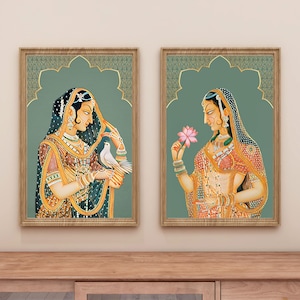 May include: Two framed paintings of women in traditional Indian clothing. The woman on the left is holding a white dove, while the woman on the right is holding a pink flower.