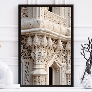 May include: A framed photograph of a white stone building with intricate carvings and a balcony. The building has a light beige color and the carvings are detailed and ornate.
