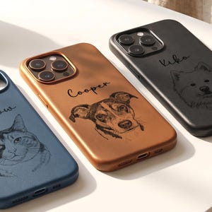 Puede incluir: Tres fundas para smartphone en azul, cobre y negro, cada una con un retrato de línea personalizado de una mascota y un nombre. La funda azul muestra un gato llamado Willow, la funda de cobre un perro llamado Cooper y la negra un perro llamado Kika.