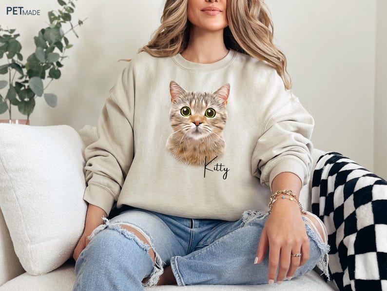 a woman sitting on a couch wearing a cat sweatshirt