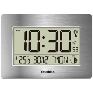 May include: A silver digital clock with a large display showing the time as 10:30 am. The clock also displays the date as 30/12, the day of the week as MON, and the temperature as 25.0 degrees Celsius. The clock has a silver frame and a black background.
