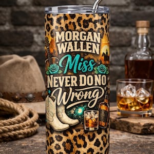Op de afbeelding: Een roestvrijstalen beker met een luipaardprint en de tekst "Morgan Wallen Miss Never Do No Wrong". De beker heeft een rietje en afbeeldingen van cowboylaarzen, een gitaar en een fles whisky.