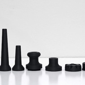 May include: Eight black objects of different shapes are displayed in a row. The objects include cylindrical, conical, and rounded forms, all with a matte finish. The items are presented against a white background.