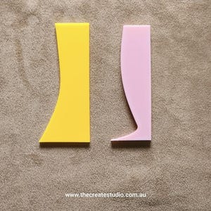 May include: Two plastic tools for applying resin, one yellow and one pink. The tools are shaped like a curved rectangle and a curved rectangle with a pointed end.