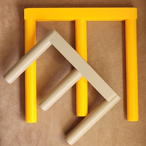 May include: A set of three yellow and beige wooden toy building blocks. The blocks are arranged in a triangular shape.