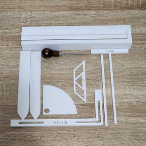 May include: A selection of white craft tools and accessories, including rulers, a curved blade, and a wooden-handled awl. The image also shows a piece that is 12 x 7 cm and a 5 mm piece.