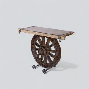 May include: A wooden side table with a repurposed wagon wheel base. The table has a rectangular top with a light-coloured surface and metal accents. The wheel is dark brown with visible wood grain, and the table rests on small wheels.
