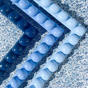 May include: A set of three blue and white ceramic frames with a decorative pattern. Each frame is adorned with a row of blue spheres.