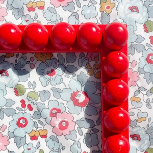 May include: A red picture frame with a rounded edge and a floral pattern background.