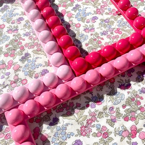 Pink wooden bobbin frames on Liberty London fabric