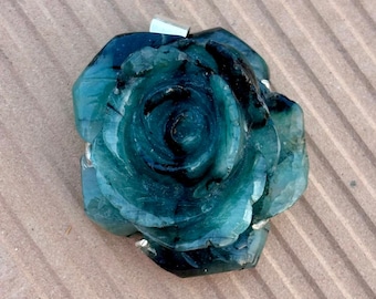 May include: A carved teal rose pendant with a silver bail. The gemstone pendant features detailed petals and a dark centre. The rose is a unique, handcrafted piece of jewellery.