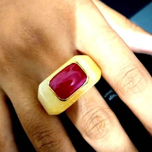 Peut inclure: Une bague en or avec une grande pierre précieuse rouge rectangulaire sertie dans un cadre rectangulaire blanc.