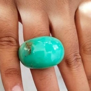 May include: A large, bright turquoise ring made of natural stone. The ring is smooth and rounded, with a slightly irregular shape.