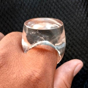 May include: A clear, round, plastic ring with a smooth, polished surface.