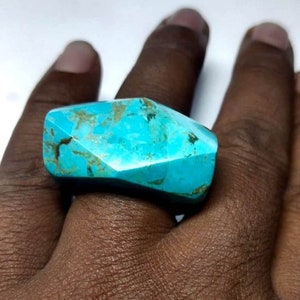 May include: A turquoise ring with a unique, faceted design. The ring is made of natural turquoise and has a blue-green colour with brown veins.