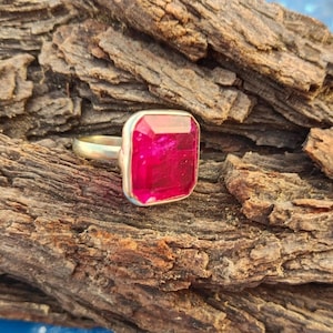 Può includere: Un anello d'argento con una grande pietra preziosa quadrata di colore rosa brillante.