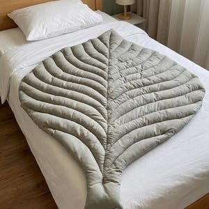 Tapete de atividades reversível em algodão orgânico com estampa de folhas, ideal para bebês que querem brincar de bruços.