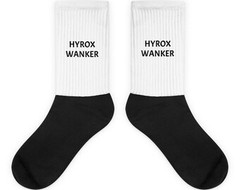 May include: A pair of white crew socks with black heels and toes. The socks have the text "HYROX WANKER" printed in black on the white portion of the socks.