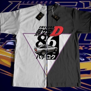 Könnte beinhalten: Ein weißes und schwarzes T-Shirt mit einem geteilten Design. Die linke Seite zeigt ein weißes Auto mit dem Text "INITIAL D" und "86" in Rot und Schwarz. Die rechte Seite zeigt einen schwarzen Hintergrund mit dem Text "INITIAL D" und "86" in Weiß. Das Auto ist ein weißer Toyota AE86.