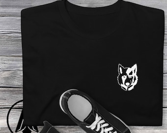 May include: Black t-shirt with a white wolf silhouette graphic on the front. The t-shirt is laying on a wooden surface with a pair of black sneakers.