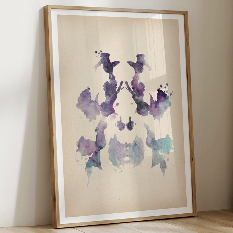 May include: A symmetrical inkblot image in shades of purple, blue, and gray. The inkblot is framed in a light wood frame.
