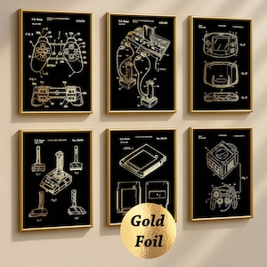 May include: Six framed patent prints showcasing gold foil illustrations of retro video game controllers and consoles on a black backdrop. The prints depict diagrams of joysticks, gamepads, and handheld consoles, with gold frames.