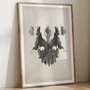 Puede incluir: Una imagen de mancha de tinta negra y blanca, similar a las que se utilizan en la prueba de Rorschach, sobre un fondo beige. La mancha de tinta es sim&eacute;trica y se asemeja a un par de caras o a una mariposa.