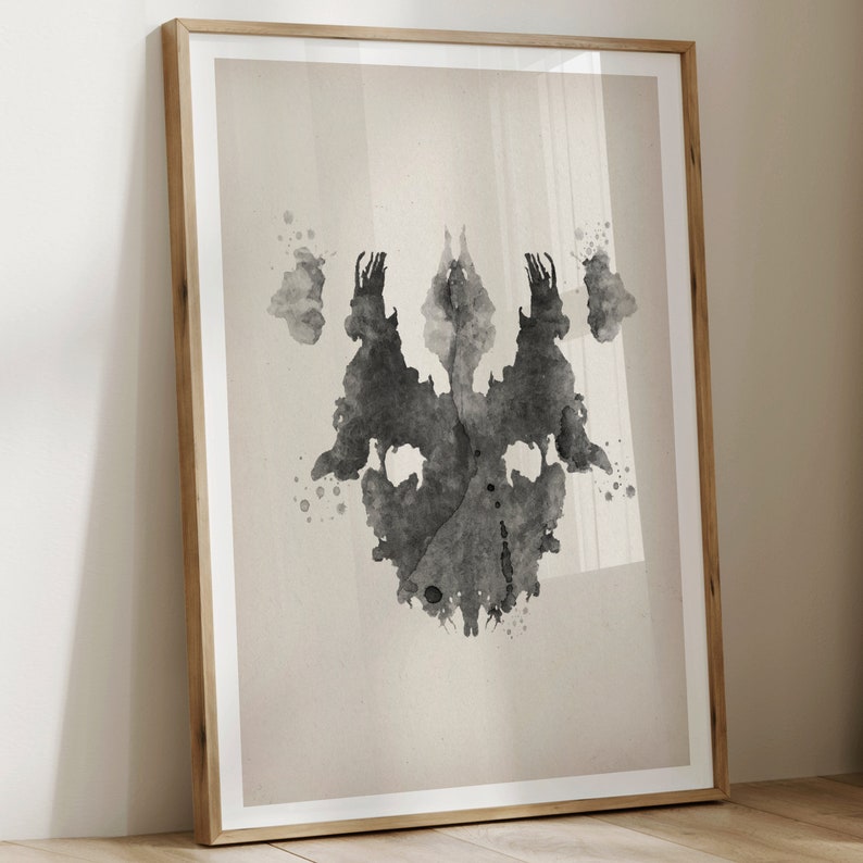 Puede incluir: Una imagen de mancha de tinta negra y blanca, similar a las que se utilizan en la prueba de Rorschach, sobre un fondo beige. La mancha de tinta es sim&eacute;trica y se asemeja a un par de caras o a una mariposa.