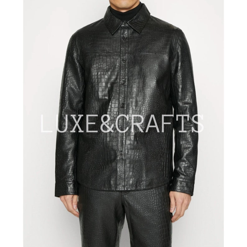 May include: A black leather shirt with a crocodile pattern. The shirt has a button-down front and long sleeves.