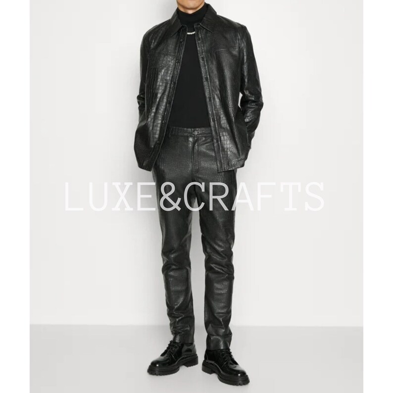 May include: A black leather jacket and matching pants with a crocodile-embossed pattern. The jacket has a button-up front and long sleeves. The pants have a slim fit and a straight leg.