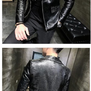 Pu&ograve; includere: Giacca in pelle nera strutturata con chiusura a zip e revers a lancia. La giacca presenta un sottile motivo a forma di rettile ed &egrave; indossata sopra un top nero. L'immagine mostra la parte anteriore e posteriore della giacca.