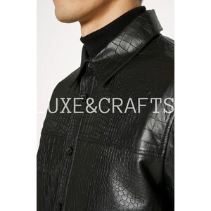 May include: A black faux leather shirt with a crocodile pattern. The shirt has a button-up front and a collar.