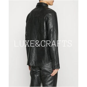May include: A black leather shirt with a crocodile pattern. The shirt has a button-up front and long sleeves.