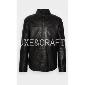 May include: A black leather shirt with a crocodile pattern. The shirt has a button-down collar and long sleeves.