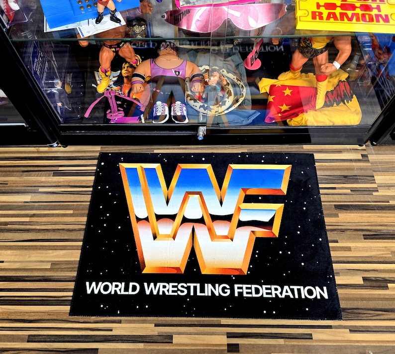 May include: Black rectangular mat featuring the World Wrestling Federation logo in blue, orange, and white. The words "WORLD WRESTLING FEDERATION" are printed in white below the logo. The mat has a starry background.