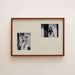 May include: A rectangular wooden frame containing two black and white photographs. Each photo depicts a person with long hair wearing oval-shaped sunglasses. The left photo shows the person with arms raised, while the right photo shows a portrait.