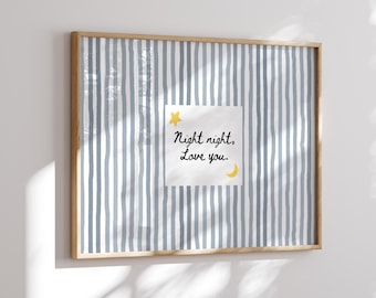 May include: A framed print with a light wood frame. The artwork features a blue and white striped background. A white square with the text "Night night, Love you." is centered, with a yellow star and crescent moon.