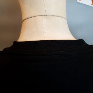 Puede incluir: Camiseta negra con cuello de canal&eacute;.